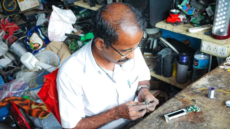 A technician repairing a part at his bench in an electronics repair shop
